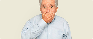 Senior man with a surprised expression covering his mouth, illustrating common dental coverage mistakes seniors make.