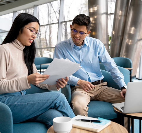 Two professionals discussing employee benefit solutions, reviewing documents in a modern office setting, emphasizing collaboration and strategic planning.