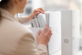 Woman organizing documents in a filing box, symbolizing streamlined underwriting and efficient policy management for disability insurance.