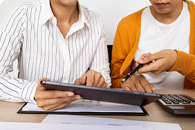 Two individuals discussing group insurance strategies, reviewing a tablet and documents, emphasizing personalized service and cost-saving solutions for employee benefits.