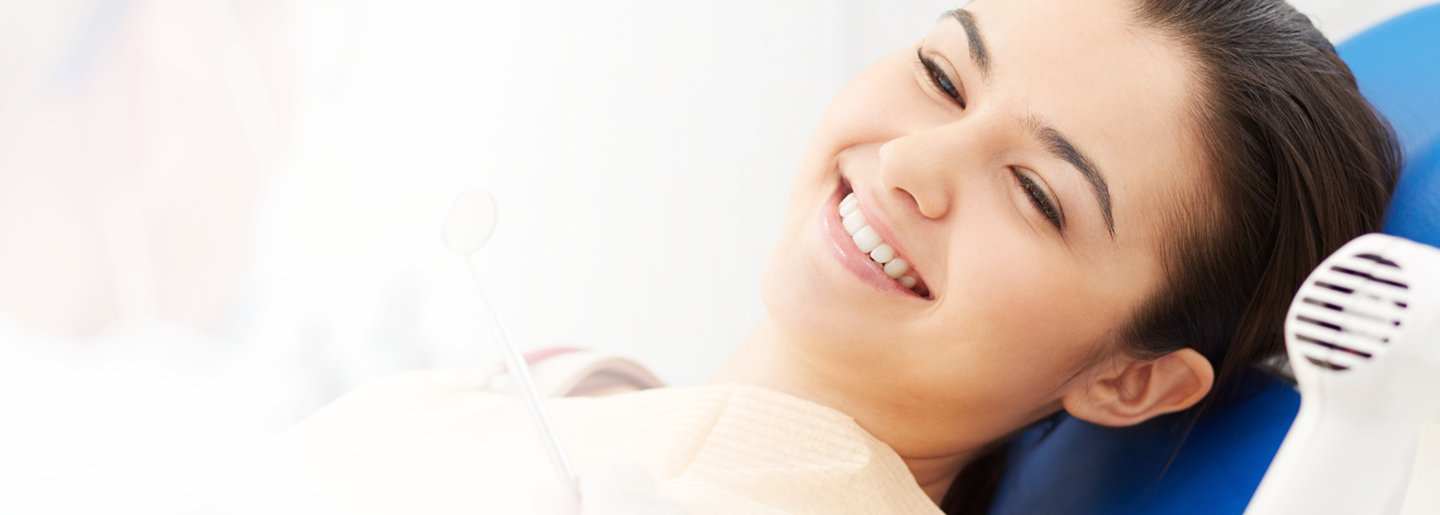 Smiling woman in dental chair, showcasing dental coverage benefits, emphasizing comprehensive care and preventive services.