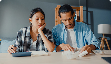 Couple reviewing financial documents and expenses, reflecting on financial planning and insurance needs.