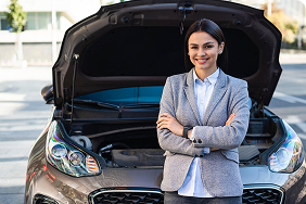 Friendly insurance agent standing confidently by a car with an open hood, representing personalized service and expertise in senior auto insurance options.