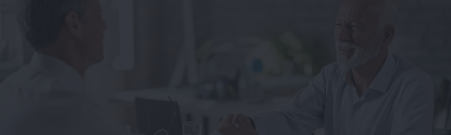 Senior man shaking hands with a financial advisor in a professional setting, illustrating trust and peace of mind in final expense insurance discussions.