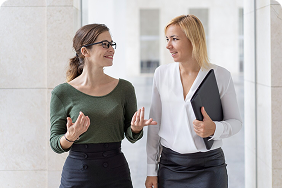 Two professional women engaged in conversation, discussing disability insurance options and tailored solutions for high-earning professionals and business owners.