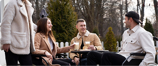 Group of young adults enjoying drinks at an outdoor café, discussing disability insurance options and financial planning.