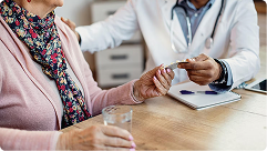 Senior woman receiving Medicare guidance from a healthcare professional, discussing options and holding a prescription card, emphasizing personalized Medicare support.