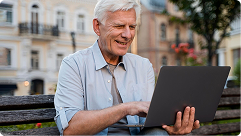 Senior man using laptop outdoors, engaging with Medicare information and resources for retirement planning.