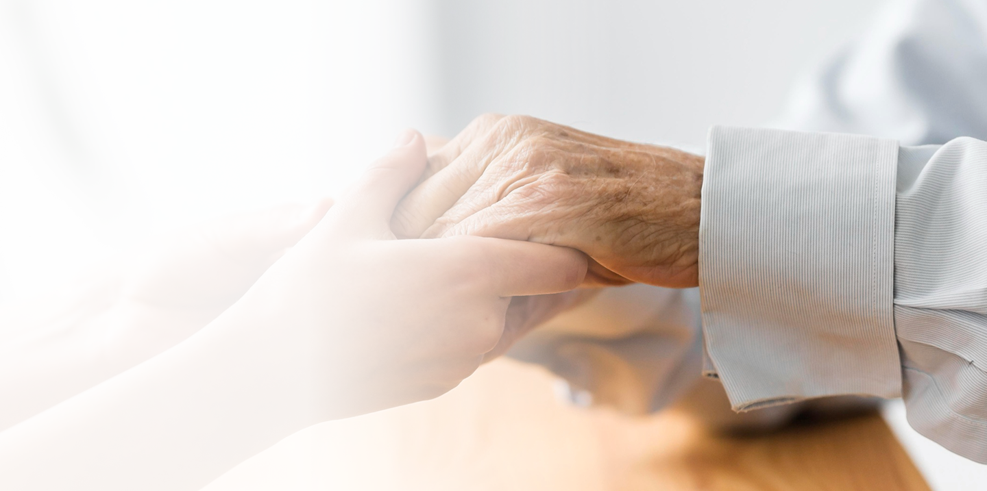 Hands of a younger person gently holding the hand of an elderly individual, symbolizing compassion and support in the context of Medicare assistance.