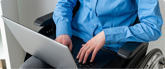 Person in wheelchair using laptop, representing accessibility in professional environments and the importance of disability income protection.