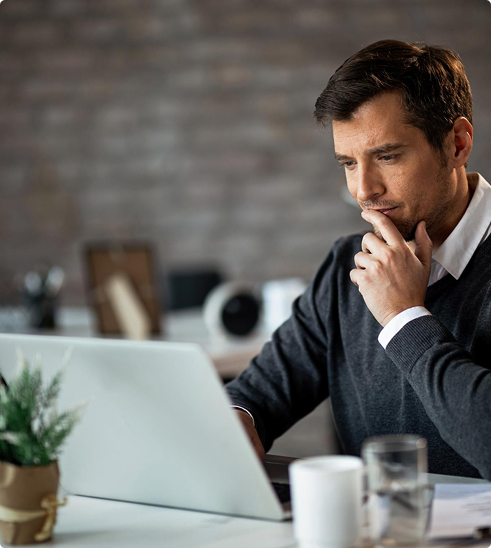 Man contemplating while working on a laptop in a home office setting, representing self-employed individuals seeking flexible health insurance options.