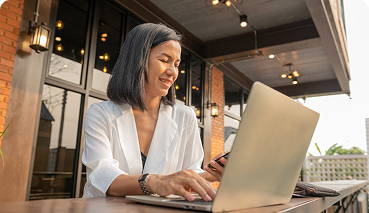 Woman using a laptop and smartphone outdoors, representing personalized assistance and flexibility in private health insurance options with Amerus Financial.