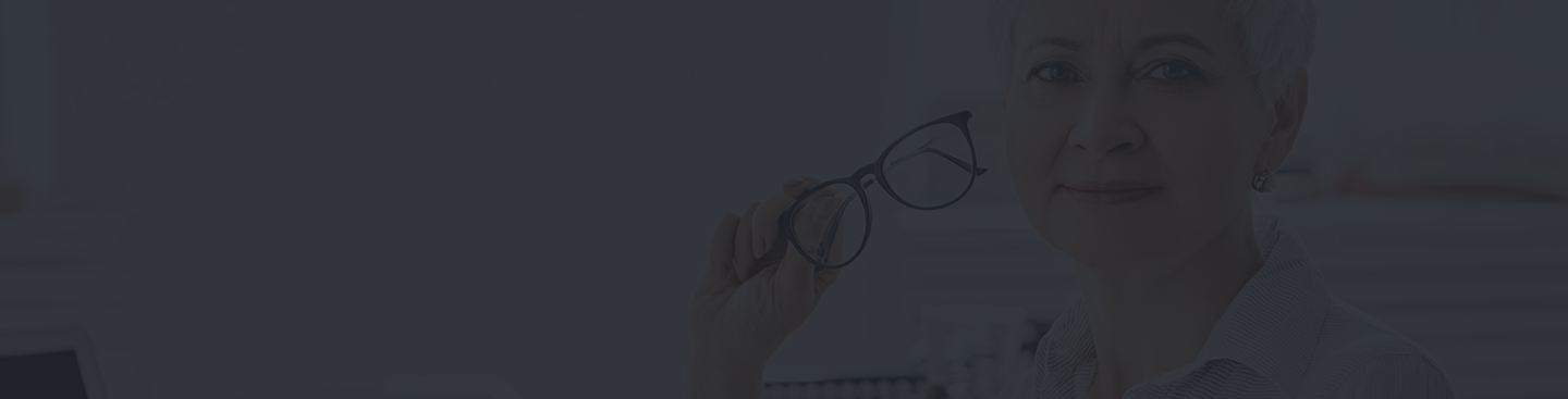 Senior woman holding glasses, emphasizing the importance of vision care and insurance for seniors.