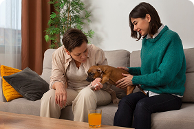 Two women interacting with a puppy on a couch, emphasizing the bond between pet owners and their pets, reflecting the supportive environment of Amerus Financial's pet insurance.