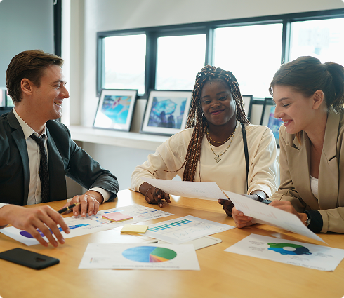 Business team collaborating at a table, reviewing charts and documents, showcasing teamwork and personalized service in commercial insurance solutions.