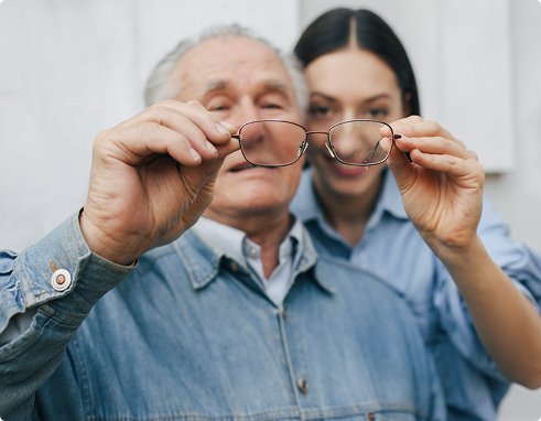 Older man and woman holding eyeglasses, representing vision insurance benefits and family eye care options.