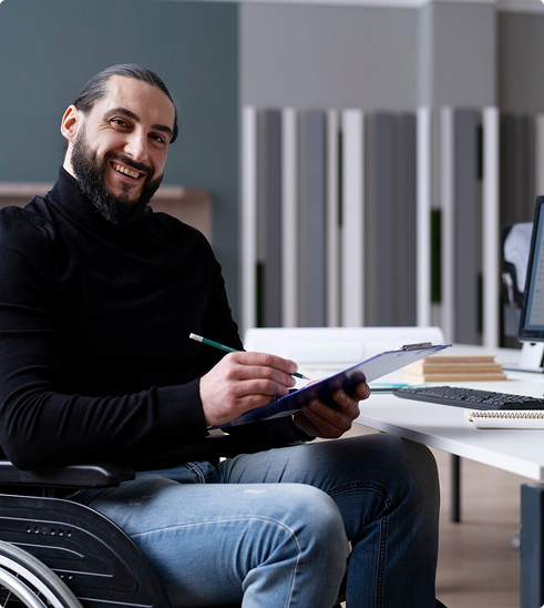 Smiling man in a wheelchair holding a clipboard and pen, representing professionals seeking individual disability income insurance for income protection.