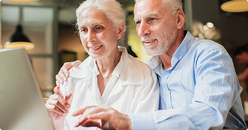 Senior couple engaging with a laptop, exploring final expense insurance options for financial security and family protection.