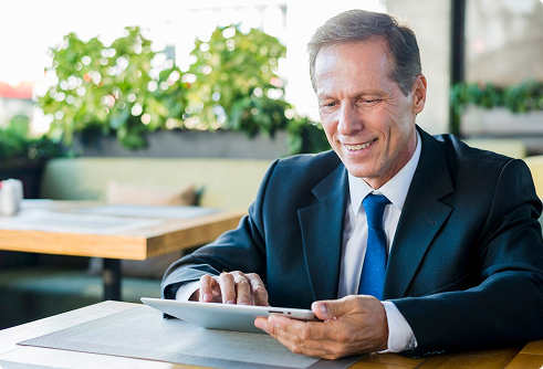 Businessman in a suit using a tablet in a café, reflecting the modern approach to financial strategies like Indexed Universal Life insurance.