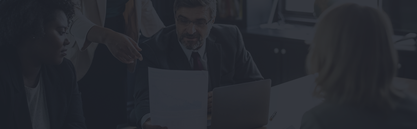 Business professionals discussing insurance and employee benefits options during a consultation meeting, with documents and a laptop on the table.