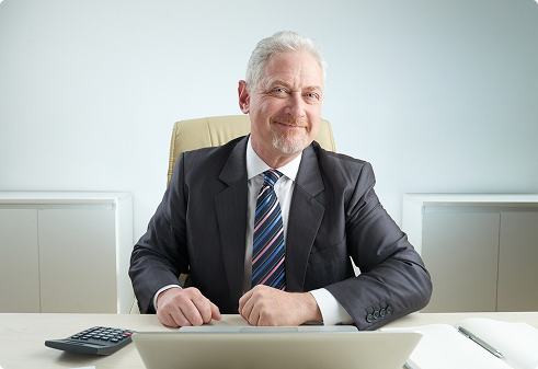 Business professional smiling at desk with laptop, emphasizing employer support and employee benefits solutions.
